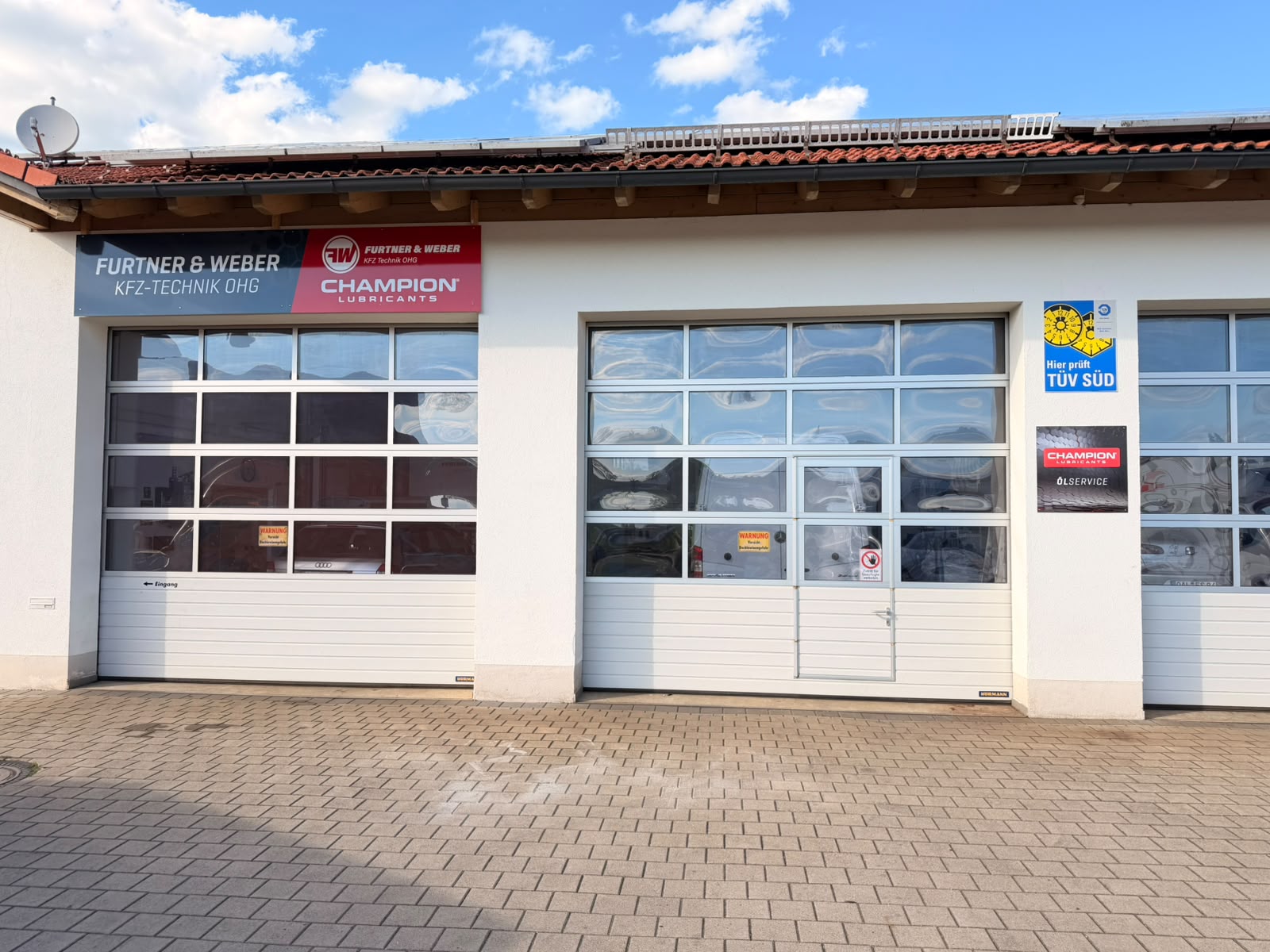 Werkstatteingang von Furtner & Weber mit TÜV-SÜD-Schild in Obergünzburg